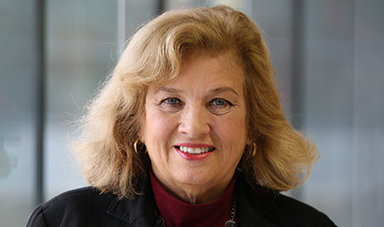 Headshot of Margaret Brooks standing in front of glass panels.