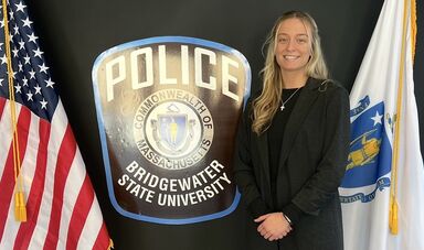 A woman stands next to a Police sign and smiles