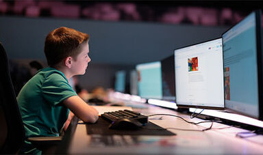 A student works at a computer with dual monitors.