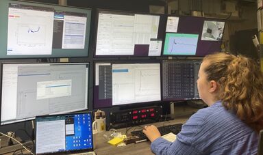 Shannon McLaughlin types while sitting in front of a large display of monitors.