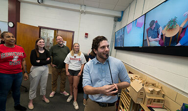 A professor and students watch a mock counseling session on a video monitor.