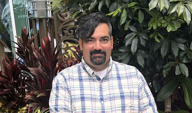 Headshot of Nathan Couto with plants in the background.