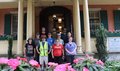 A group of people stand on the steps in front of a building