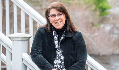 Elizabeth Englander stands on stairs with woods behind her.