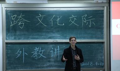 A man stands in front of a chalkboard teaching a class