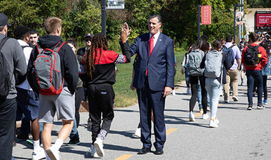 President Clark high fives a student walking along a path.