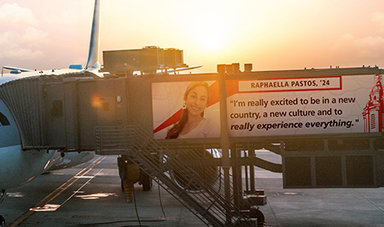 Graphics of a plane at a gate with a quote from Raphaella Pastos on the jetway saying &quot;I’m really excited to be in a new country and a new culture and to just really experience everything&quot;