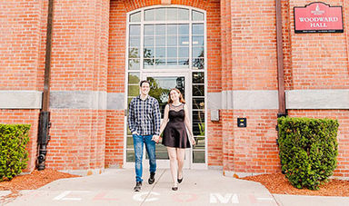 Caitlin and Joe hold hands while walking in front of Woodward Hall.