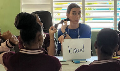 Megan Lenza teaches young students the English word “braid.”