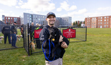 A man smiles holding a dog