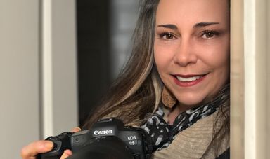 A woman smiling holding a camera