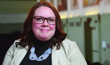 A woman wearing glasses smiles at the camera