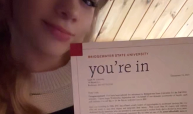 Smiling girl holds up an acceptance letter to Bridgewater State