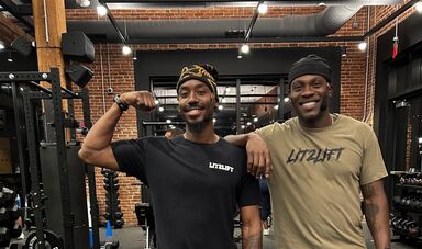 Jonady St. Germain and Darren Stephens smile while posing for a photo in a gym.
