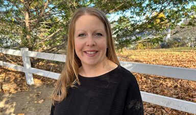 A woman with long blonde hair wearing a black shirt smiles at the camera