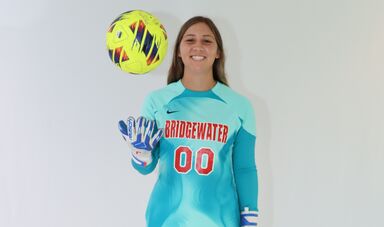 woman smiles holding a soccer ball