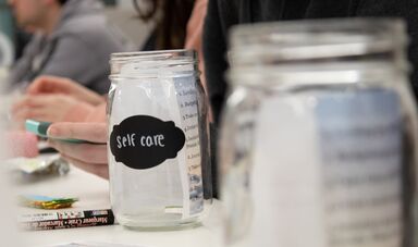 A jar sits on a table with the label self care written on it