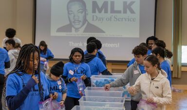 A group of people stand at a table working together in front of a MLK sign