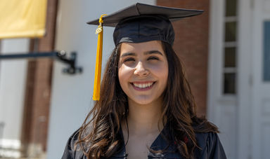 smiling woman is wearing a graduation cap and gown