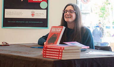 Michele Meek sits at a table with copies of her book on display