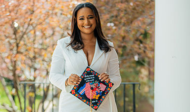 Lina Monteiro holds her colorful graduation cap, which she deocrated with a variety of designs