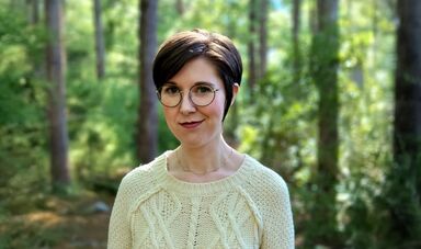 Sarah Fawn Montgomery stands in front of trees.