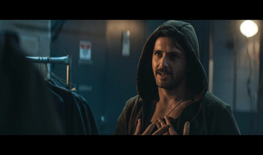 A man wearing a hood talks to another person