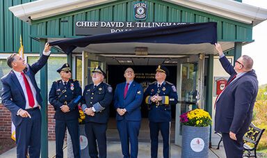Dignitaries unveil the David Tillinghast Police Station sign.