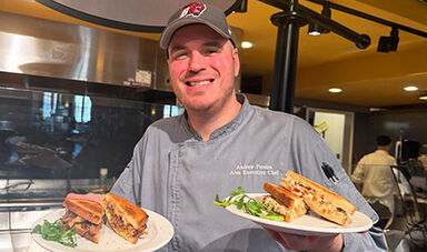 Andrew Pereira holds two plates of sandwiches.