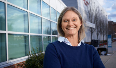 Woman stands smiling with arms crossed in front of her