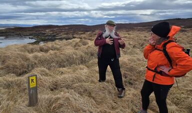 John Sexton speaks to a colleague in front of a wide Icelandic landscape.