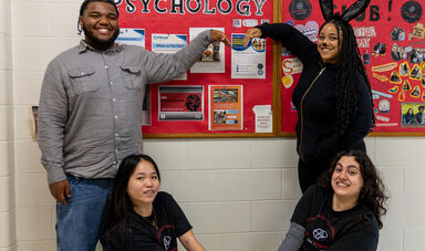 A group of people smile and stand next to a psychology sign