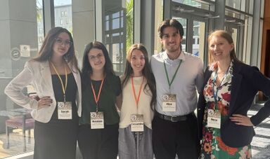 Students and a professor pose for a photo at a conference.