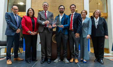 A group of people stand smiling and holding an award