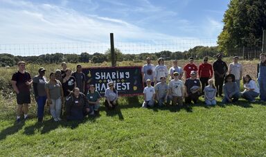 A group stands in front of a Share the Harvest Sign