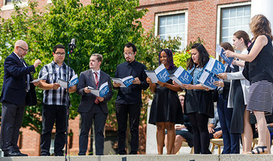 Nine members of the Social Justice Choir sing while standing on concrete steps.