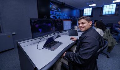 An intern works at computers in the Security Operations Center