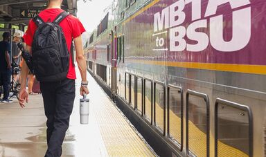 A man wearing a backpack walks towards a train