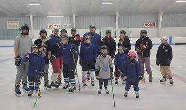 A group of people wearing hockey gear stand on the ice