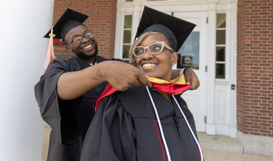 Tzaire Duponte helps put a graduation stole on his mother Thylia