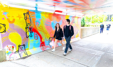 Two people walk through a colorful tunnel