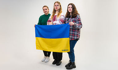 Three Ukrainian students hold their country's blue and yellow flag.