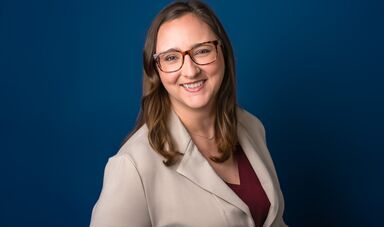 A woman wearing glasses smiles at the camera
