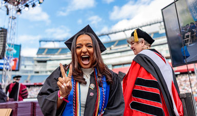 Ilina Monteiro, '24, flashing a peace sign on stage at Gillette Stadium for BSU's Commencement Ceremony