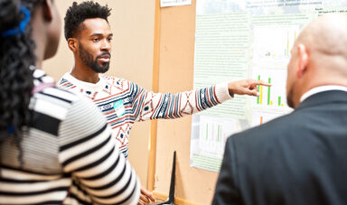 A student presenting research on sustainability points at a graph