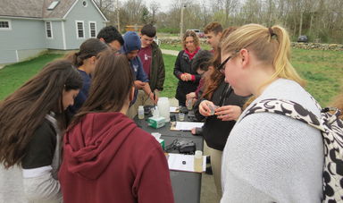 Students gathered around a table with lab kits