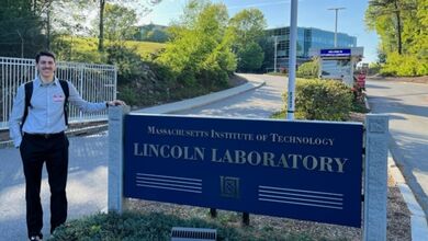 Waleed Jabak stands next to a sign for MIT Lincoln Laboratory