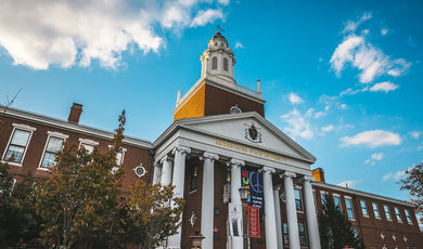 The front of Boyden Hall with leaves turning color in the trees and the Peace sign hung over the stairs