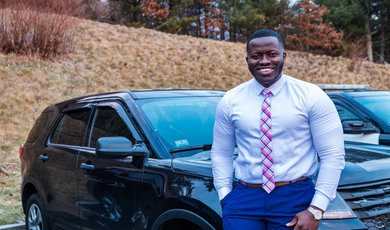 Aboubacar stands next to police cruiser