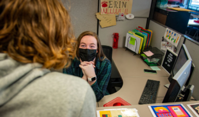 Erin Wentzel helps a student while sitting behind a desk 